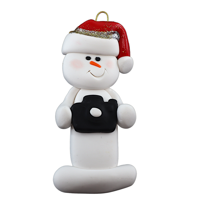 Ornament of white snowman in red hat holding a black camera.