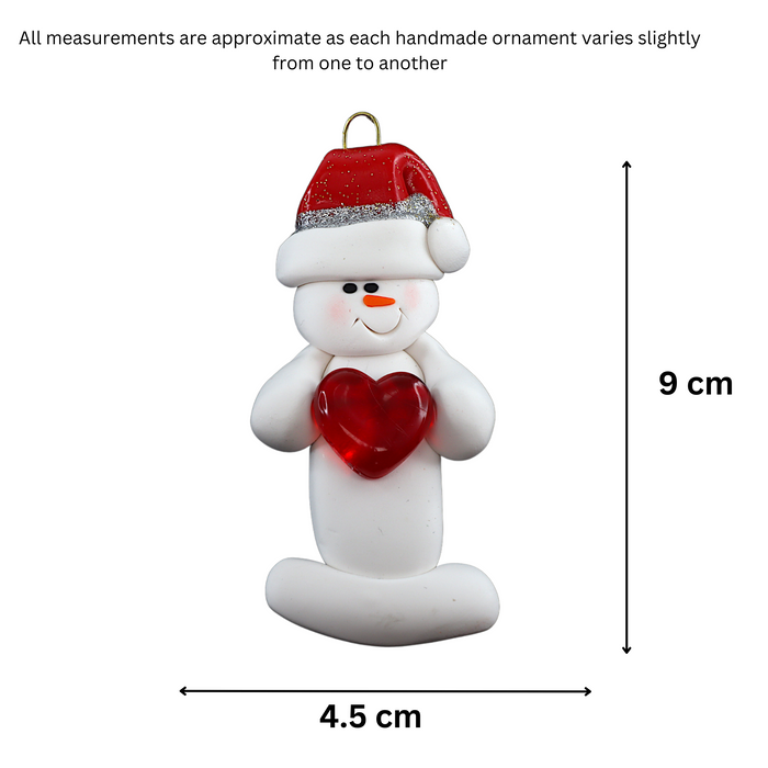 Ornament of white snowman in red hat holding a shiny red heart, graphed to show size (4.5x9cm).